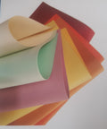 Assorted coloured manila paper sheets fanned out in warm and cool tones